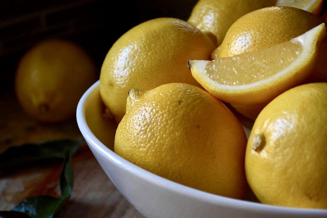 White bowl filled with lemons.