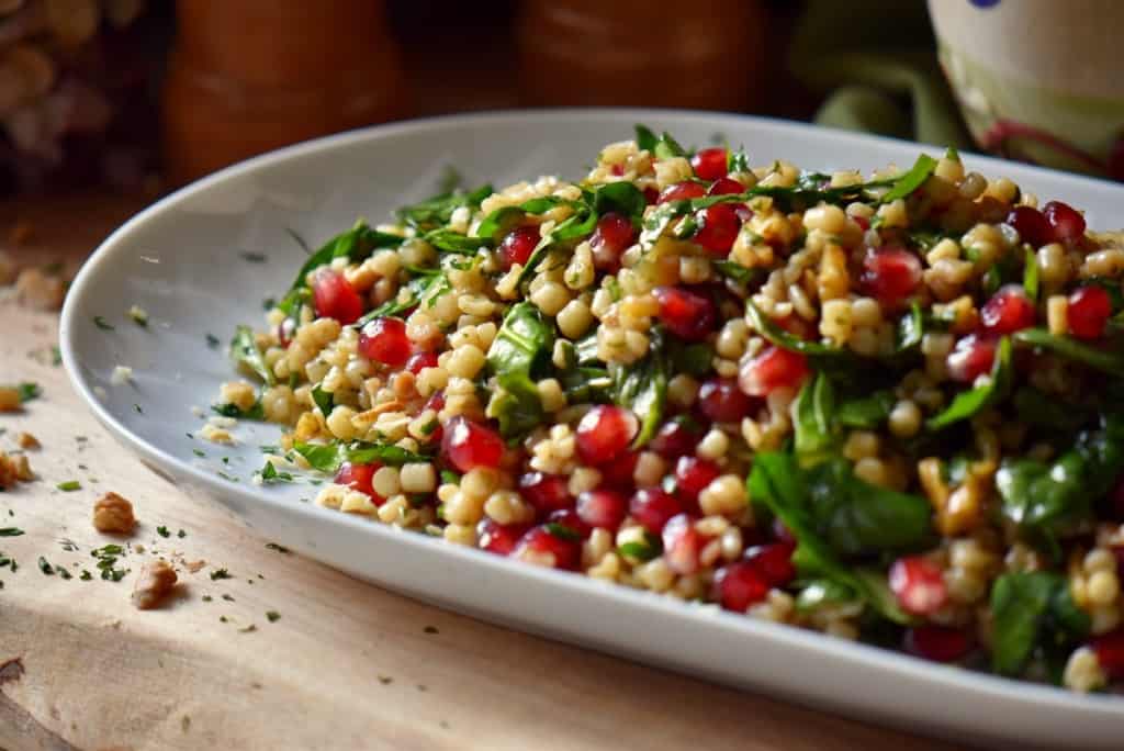 Spinach Pomegranate Salad with fregola in a large oval dish.