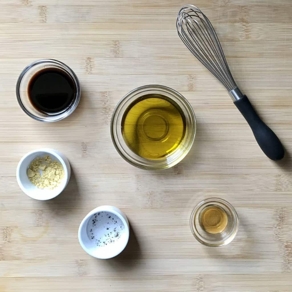 The ingredients to make the balsamic vinaigrette on a wooden table.