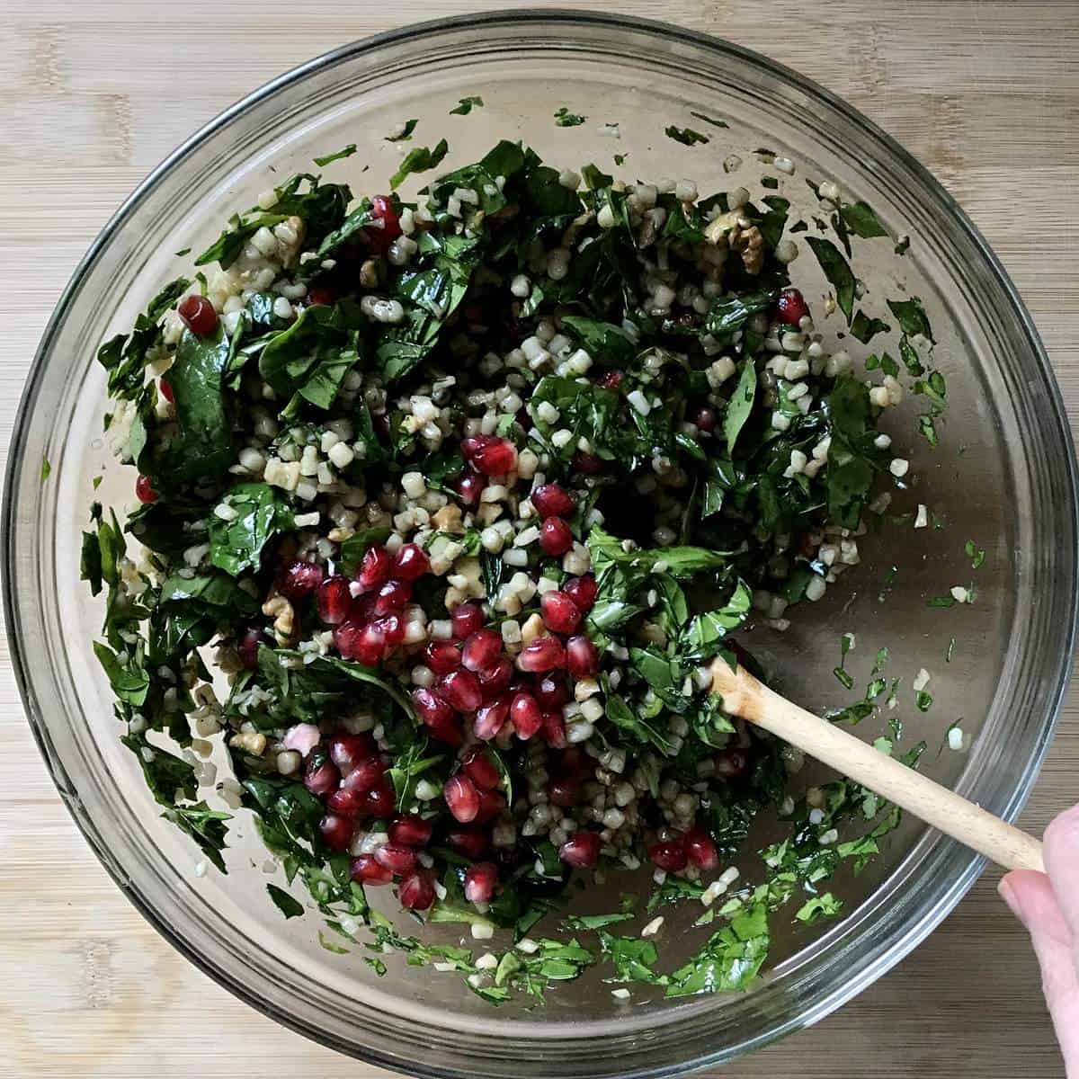 Pomegranate arils added to a spinach salad with fregola.