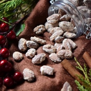 Oven Roasted Sugar Almonds are shown coming out of a jar which has been laid on its side.