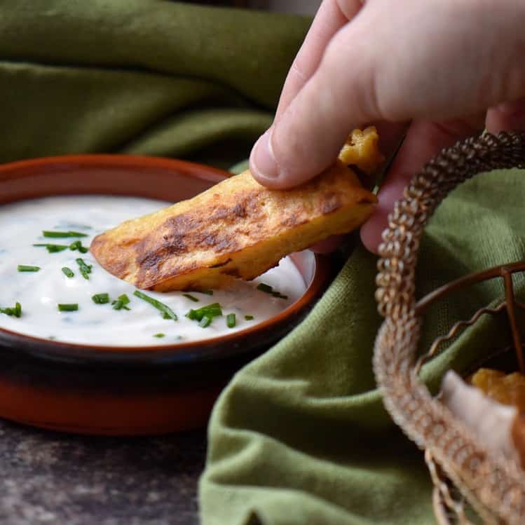 Chickpea flour sticks being dipped in a yogurt sauce.