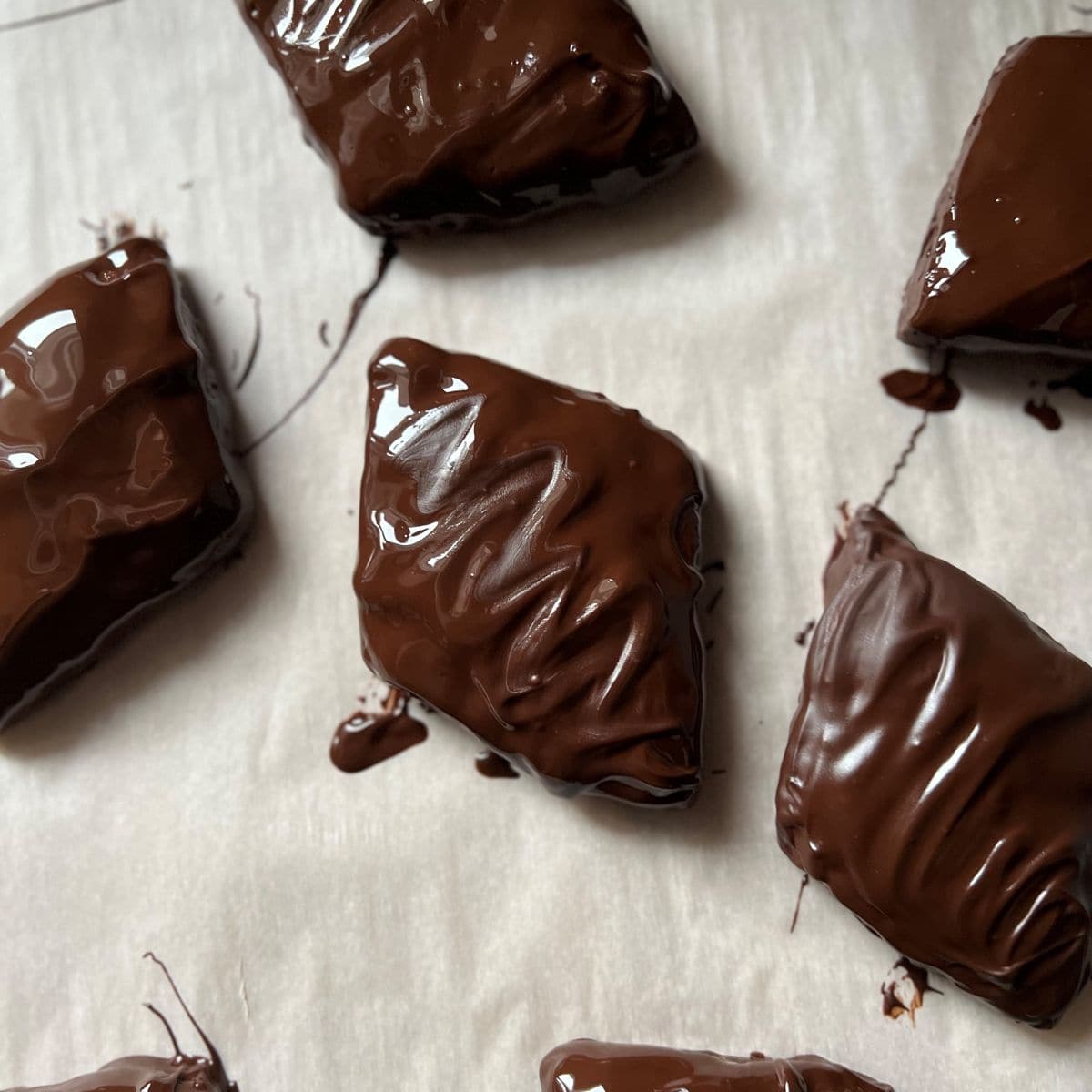 Chocolate glazed mostaccioli cookies on parchment paper.