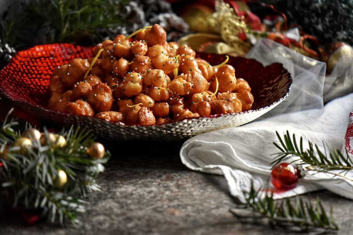 Italian honey balls in a red bowl.