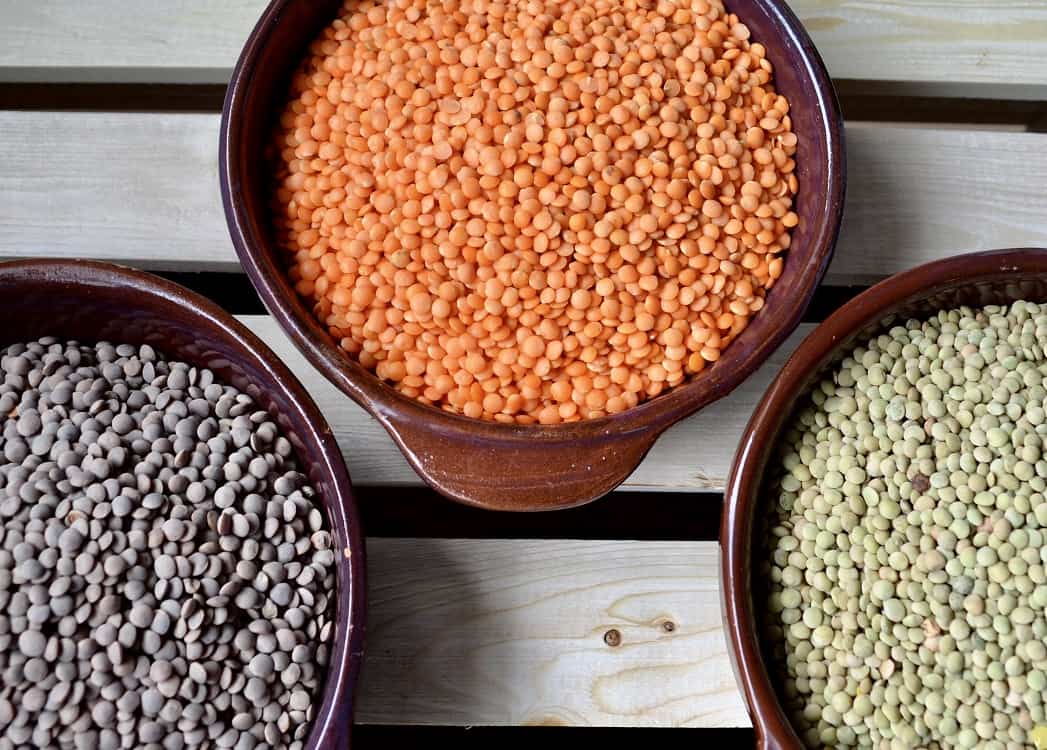 Three different types of lentils in bowls.
