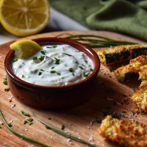 Zucchini sticks being dipped in the yogurt sauce.