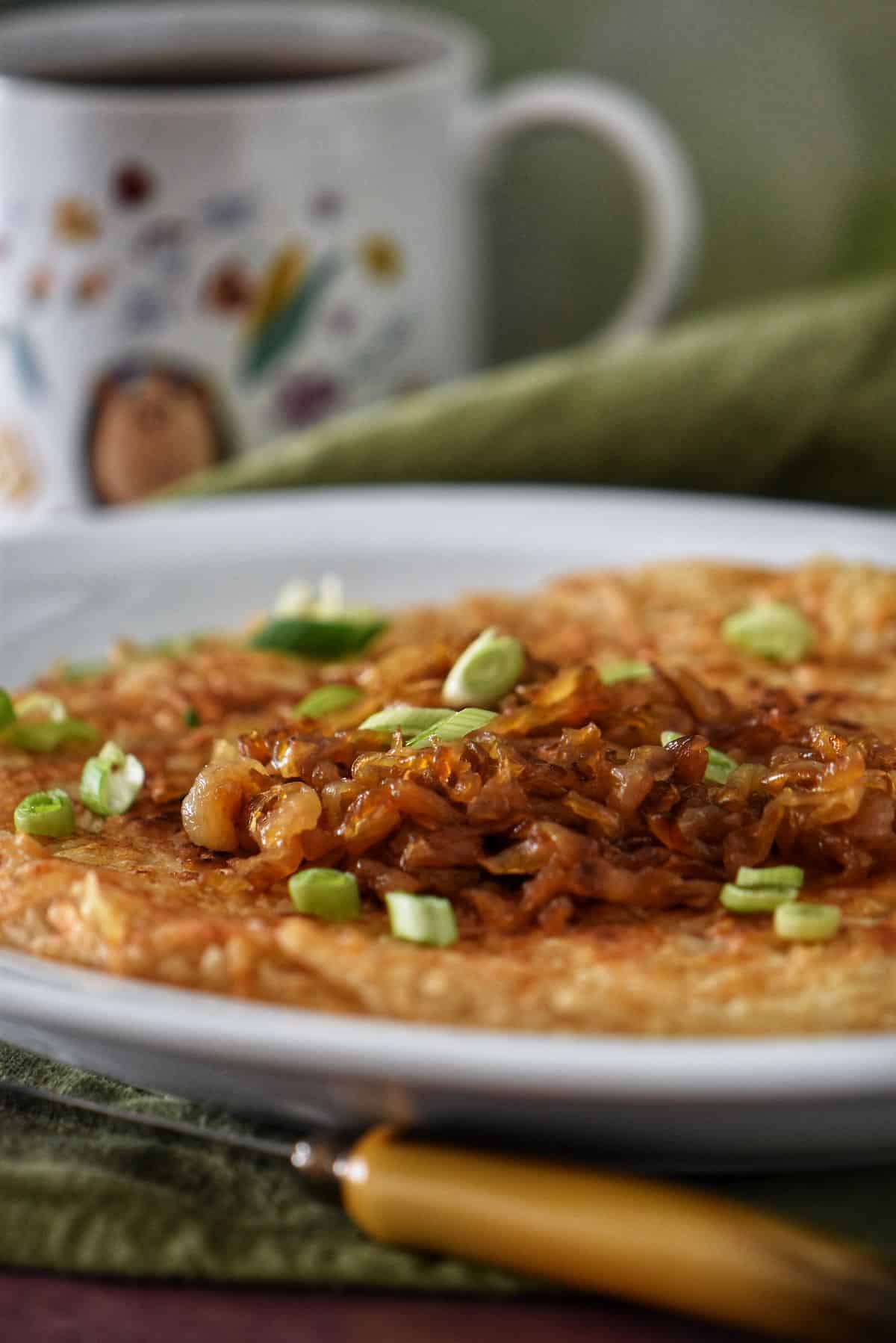 A platter of hash brown potatoes garnished with caramelized onions.