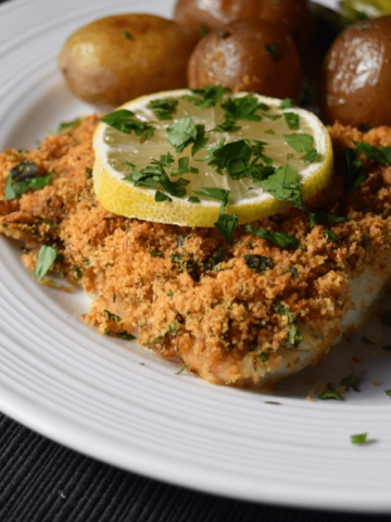 Oven baked cod fish on a white plate.