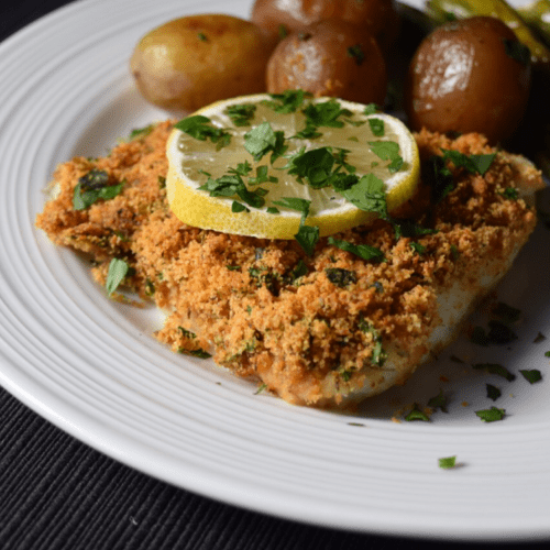 Oven baked cod fish on a white plate.