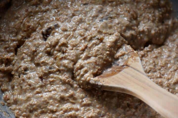 A wooden spoon is used to combine the wet and dry ingredients used to make the bran muffins.