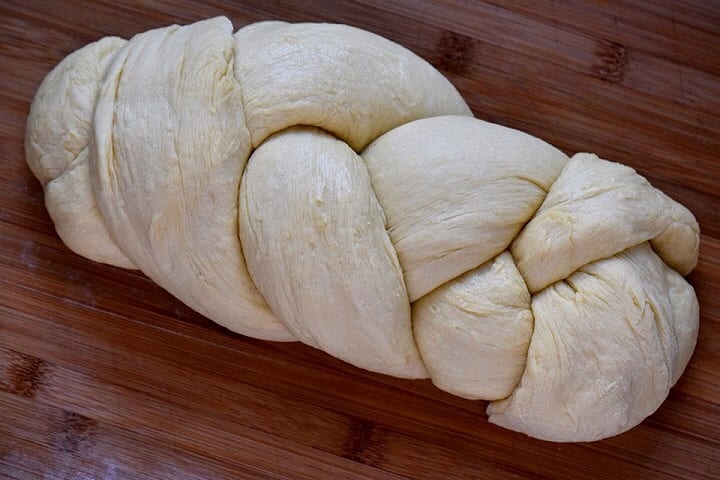 An unbaked braided version of Italian Easter Bread on a wooden board.
