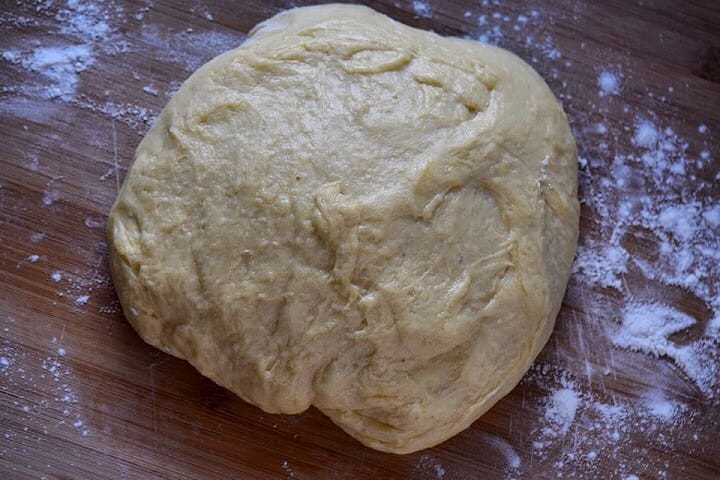 The proofed crescia dough on a floured wooden board.
