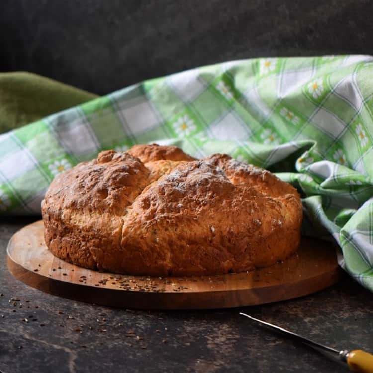 A freshly baked Irish soda bread placed on a round wooden board, ready to be sliced.