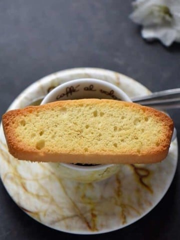 A close up of a single Italian anise biscotti on an espresso cup.