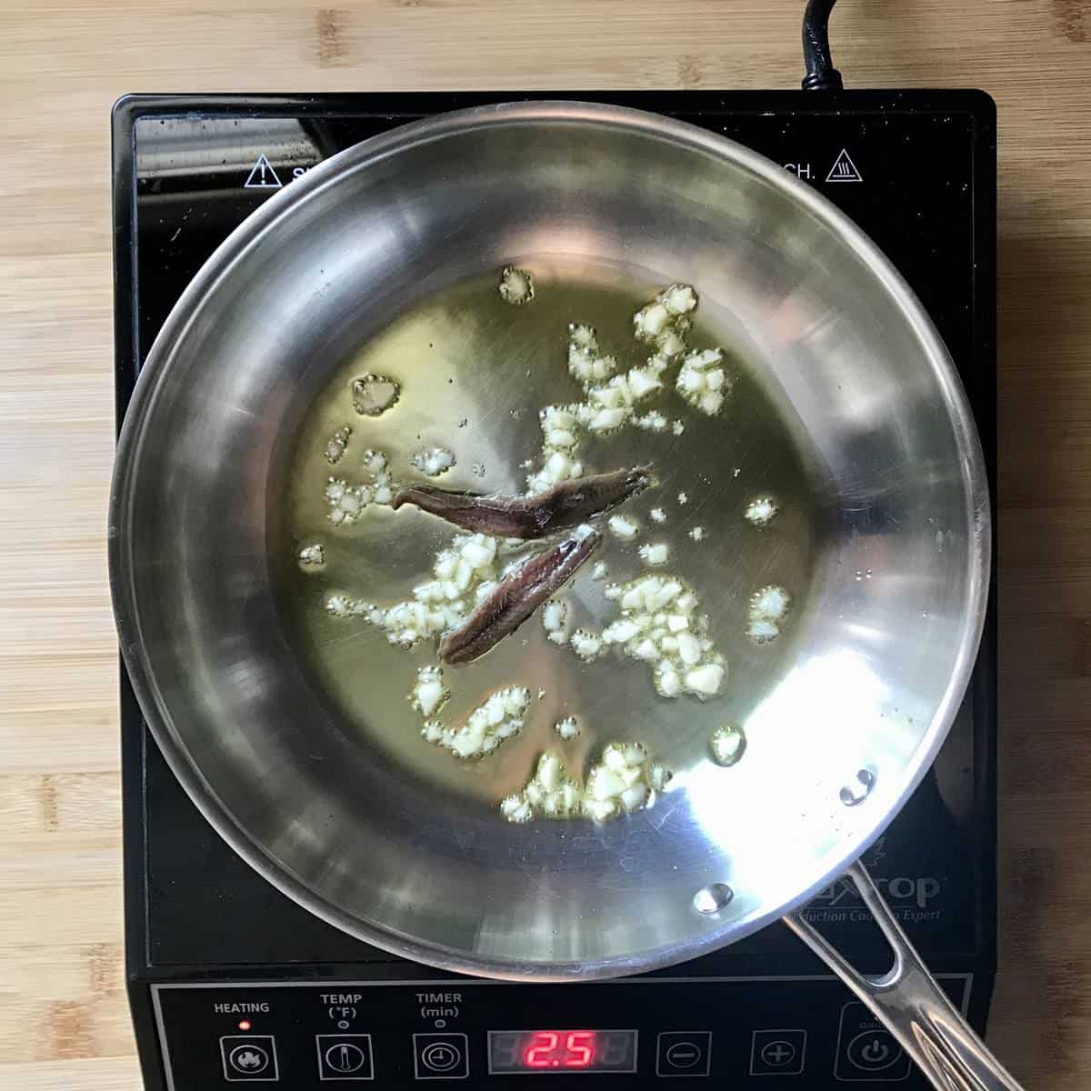 Sauteed garlic and anchovies in a pan.