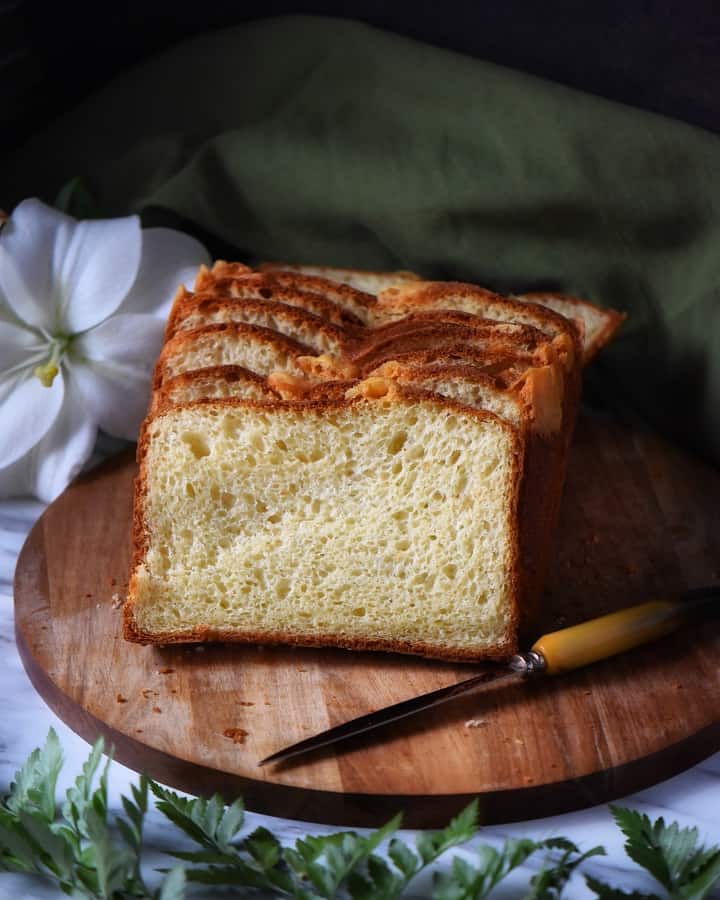 A sliced loaf of the savory Italian Easter bread on a wooden board with a knife.