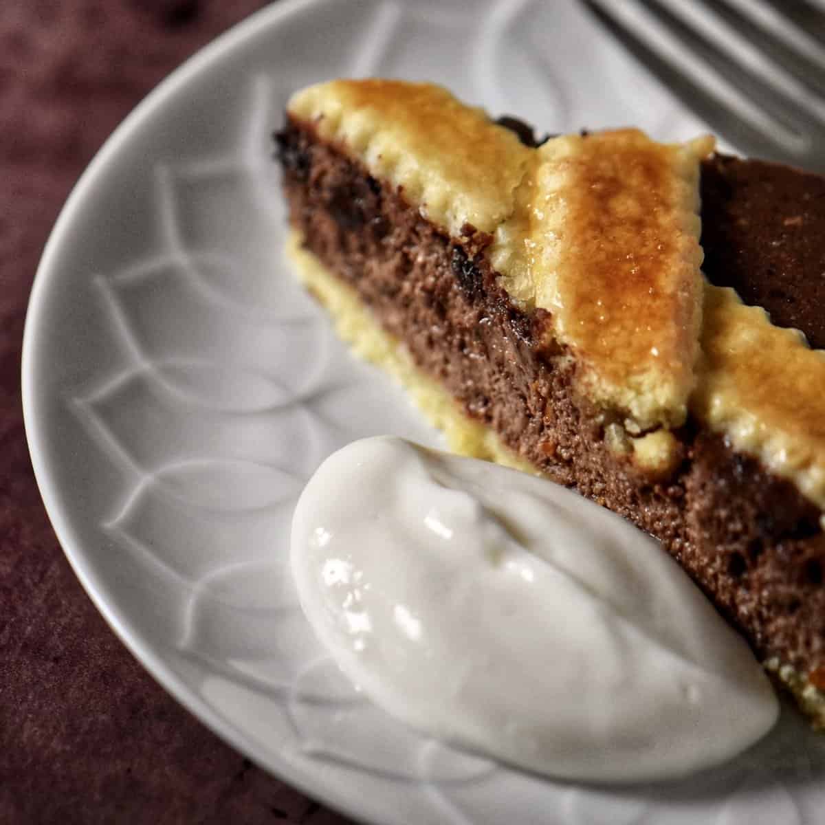 A chocolate tart topped with a lattice top on a cake platter.