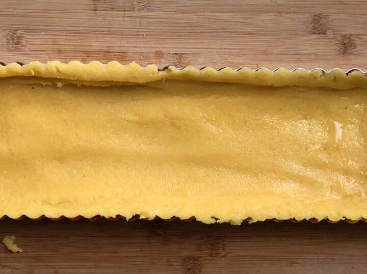 The polenta is spread out into the tart pan ready to be baked.