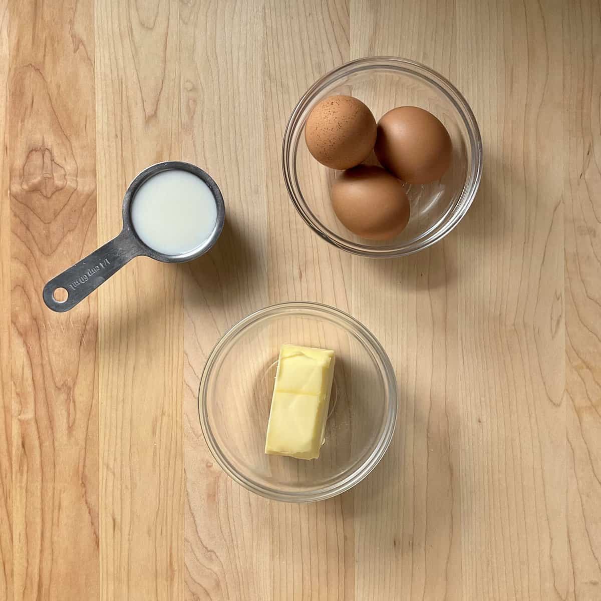 Eggs, butter and milk in bowls.