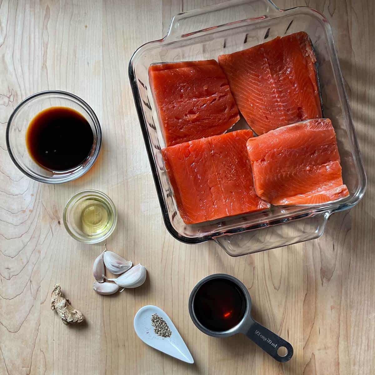 Ingredients to make a maple glazed salmon on a wooden table.