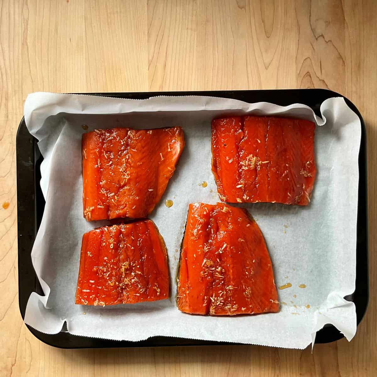 Salmon fillets on a parchment lined baking sheet. 