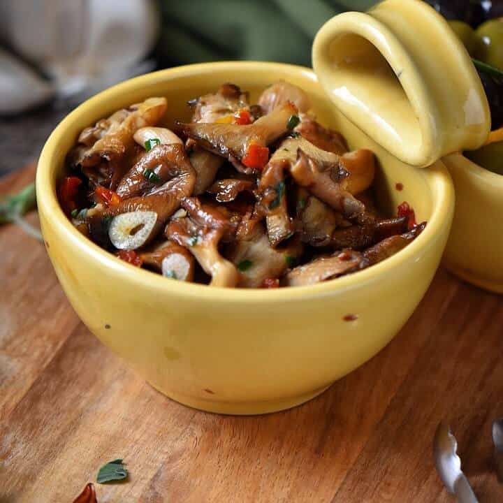 A close up shot of marinated mushrooms in a yellow bowl.