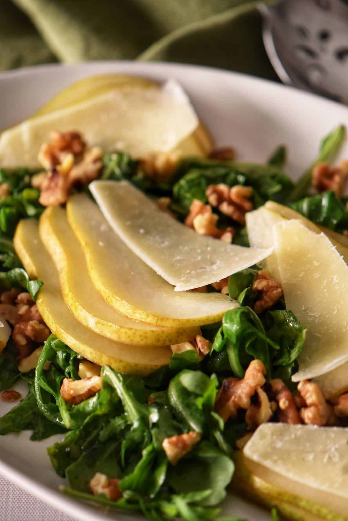 An overhead shot of a pear arugula salad in a white oval plate.