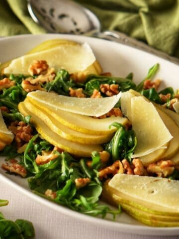 The pear arugula salad nicely arranged on a white oval platter.