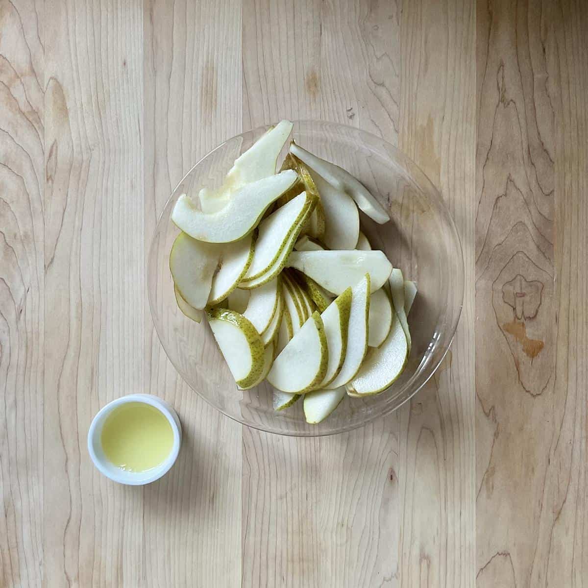 Sliced pears on a shallow dish next to a small dish of lemon juice.