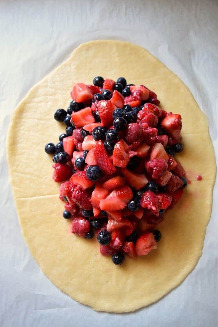 A heaping pile of assorted berries found on the rolled out crostata dough, ready to be baked.