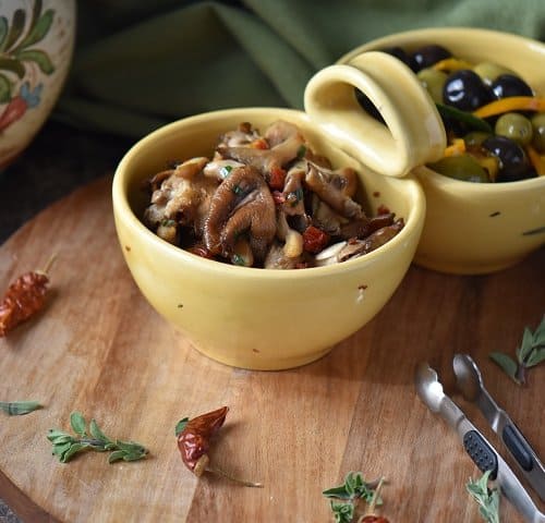 Marinated olives and marinated mushrooms are shown in two different bowls.