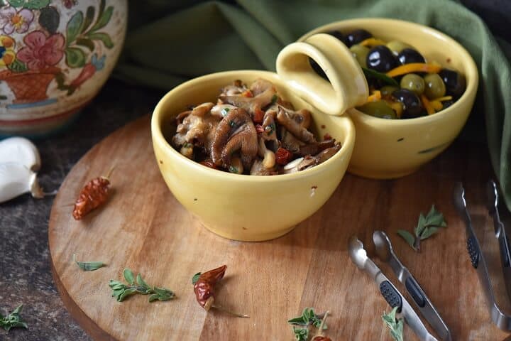 Marinated olives and marinated mushrooms are shown in two different bowls.