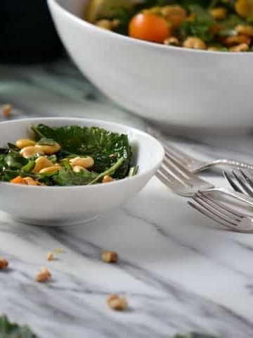 Scattered walnuts and kale leaves around a bowl of lupini salad.