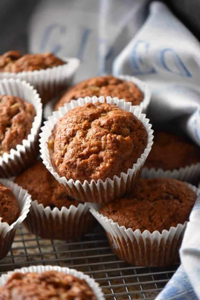 Perfectly baked moist banana muffins are piled on a cooling rack.