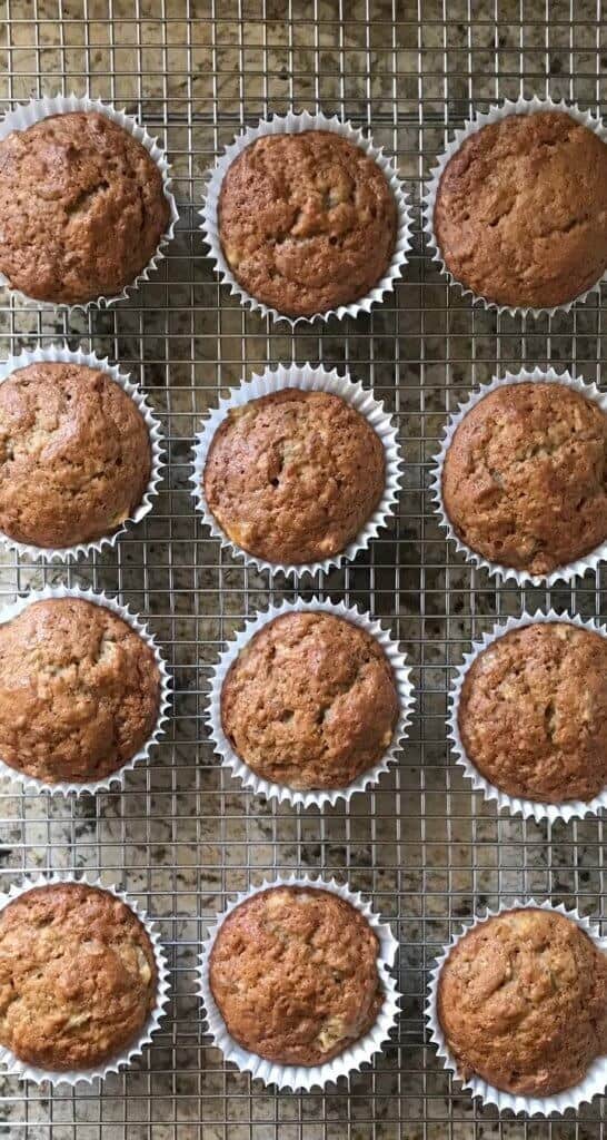 An overhead shot of a dozen banana muffins on a cooling rack.