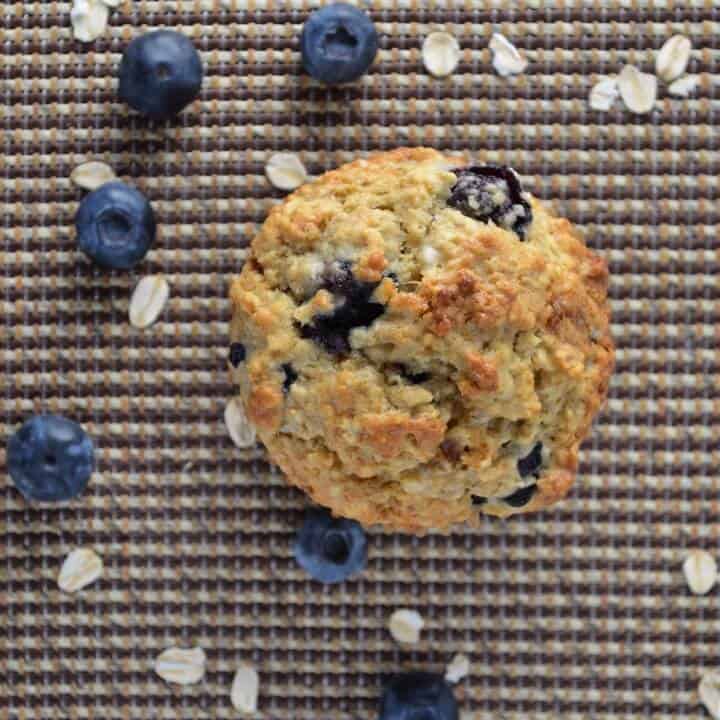 An overhead shot of a blueberry muffin surrounded by blueberries and large flakes of oats.