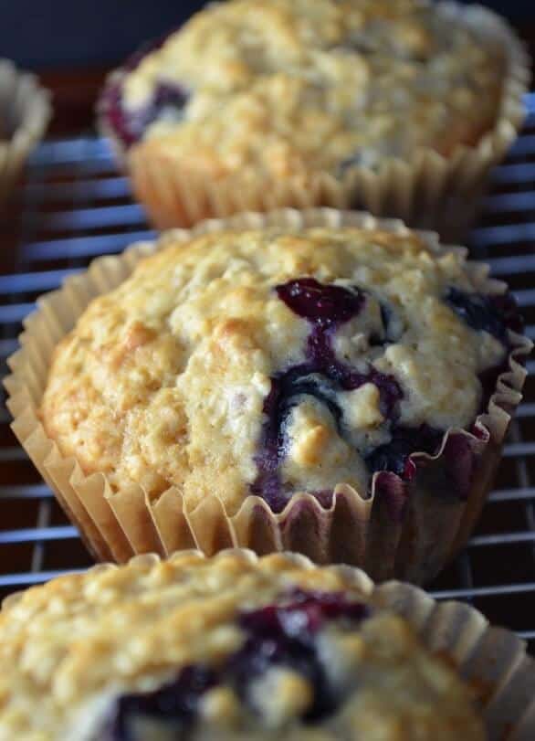 A few blueberry muffins set on a cooling rack.