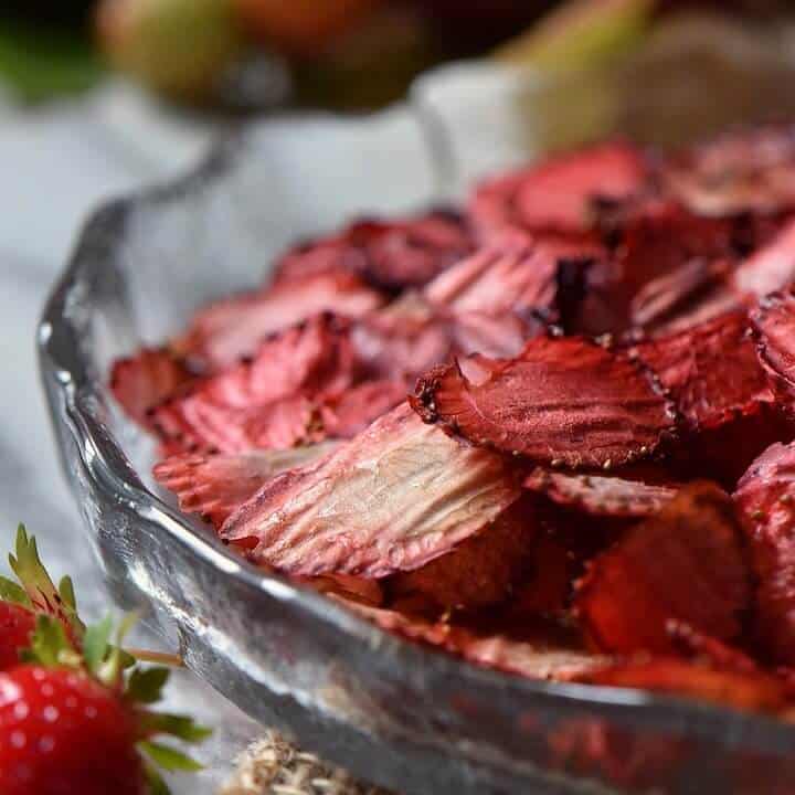 A close up shot at the crispy thin texture of a strawberry chip that has been dried on the oven.