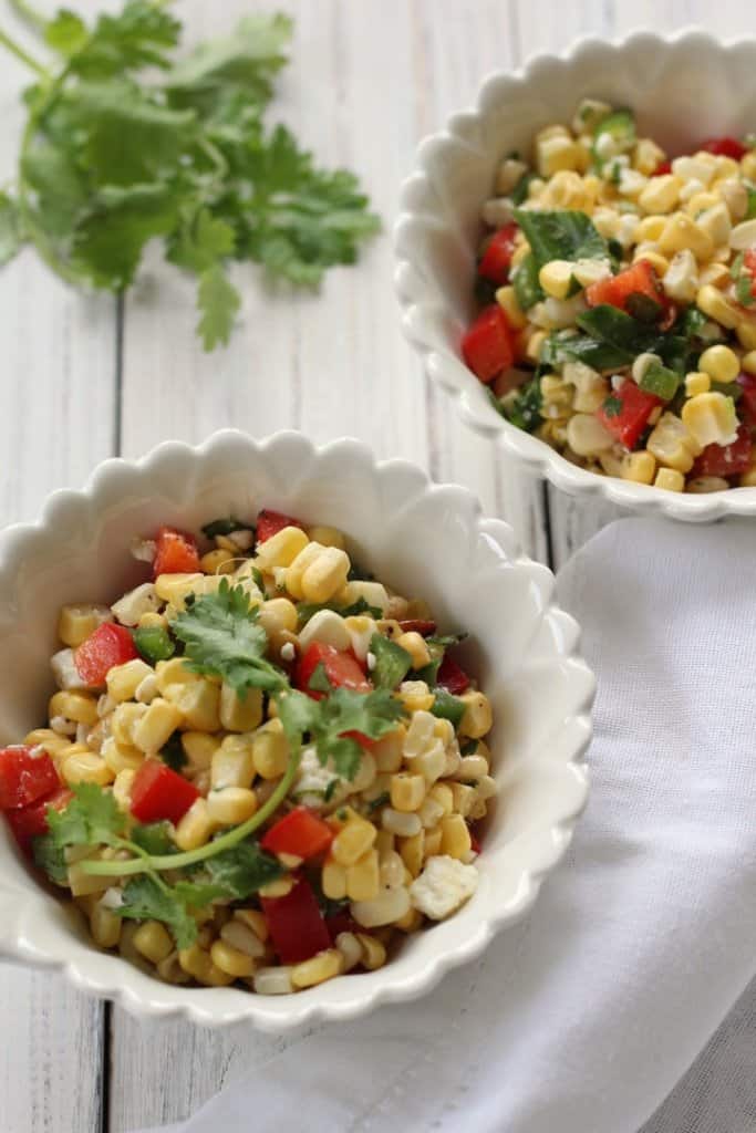An overhead shot of two bowls of sweet corn salad.