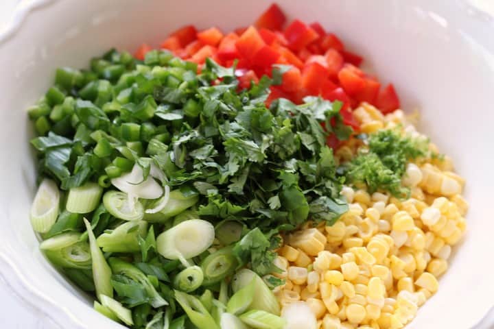 A close up shot of the chopped coriander,along side the corn and the scallions.