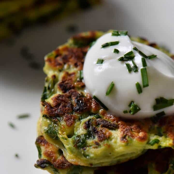 A close up of the crisp edges of a zucchini fritter served with a dollop of yogurt sauce.