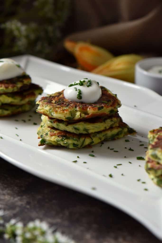 A stack of three zucchini fritters with a dollop of yogurt sauce.