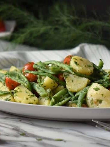 Italian potato salad with green beans and potatoes in a white serving platter.