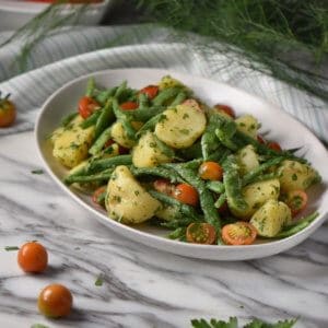 Italian potato salad with green beans and potatoes in a white serving platter.