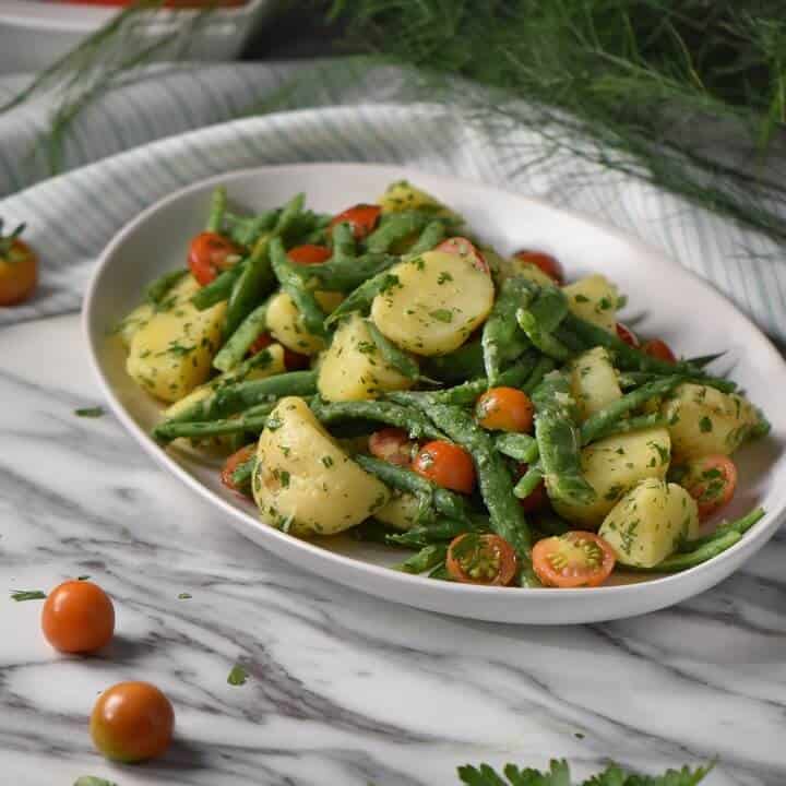 Italian potato salad with green beans and potatoes in a white serving platter.