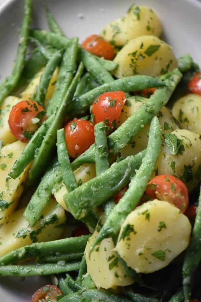 A close up shot of bright green string beans, red cherry tomatoes and creamy new potatoes.