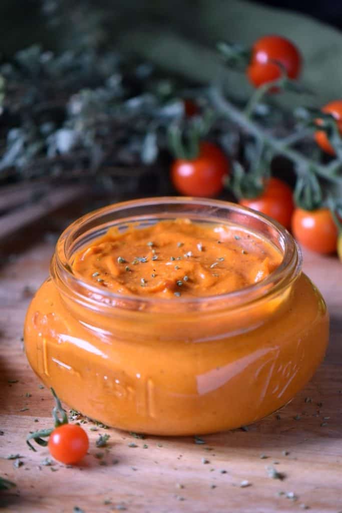 The bright color of Cherry Tomato sauce can be seen through a clear glass mason jar.