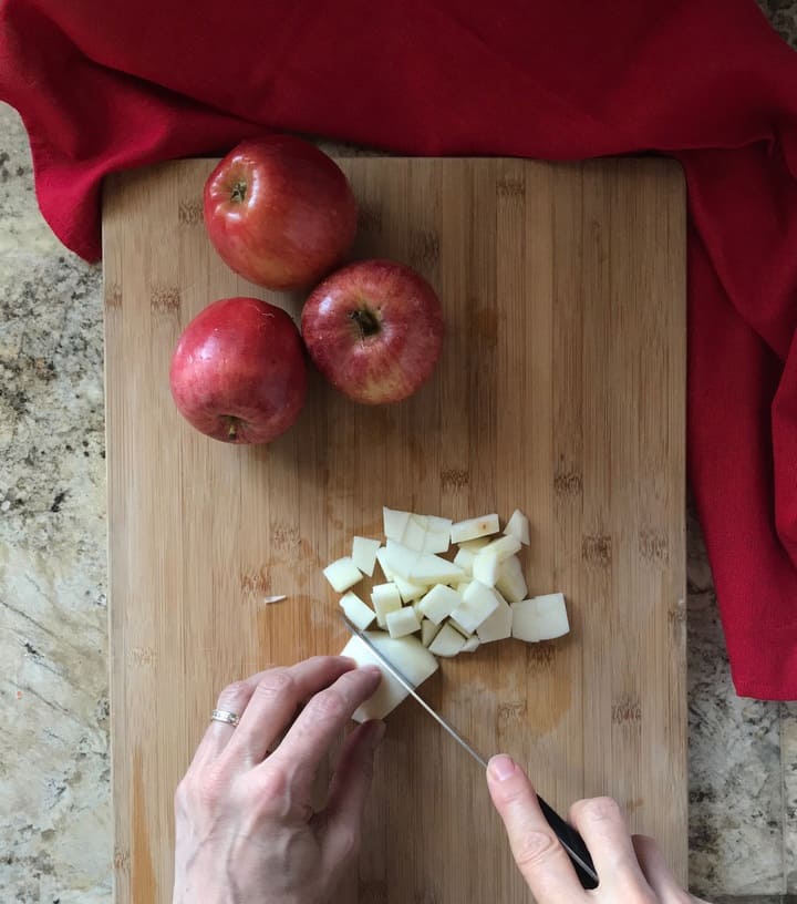 Fresh apples are being diced on a wooden board.