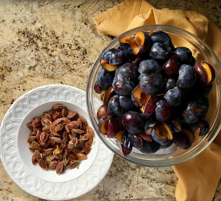 In one bowl, the pits of the prunes, in another bowl, the prune halves without the pits.