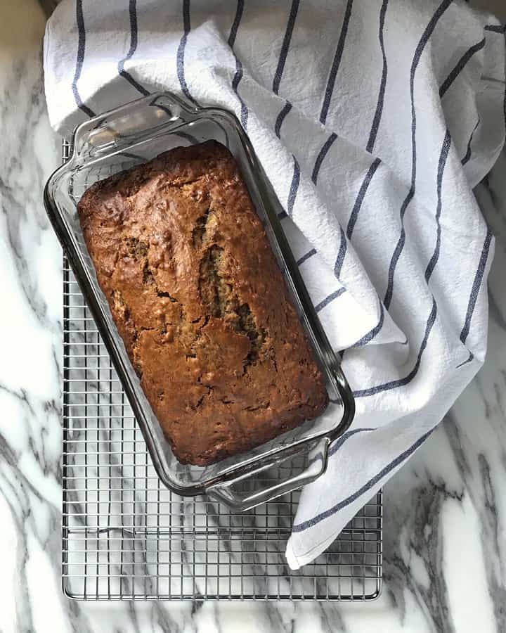 An overhead shot of a simple banana loaf cooling on a wire rack.